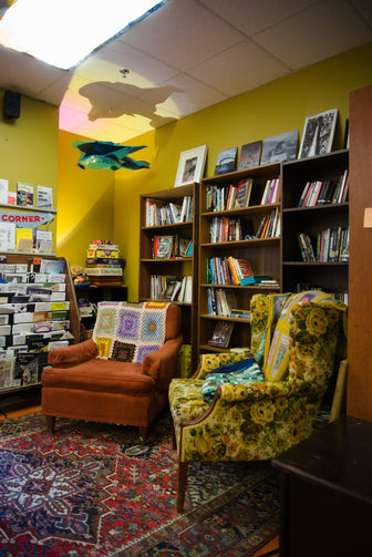 cute corner with armchairs and bookshelves and a space ship hanging from the ceiling